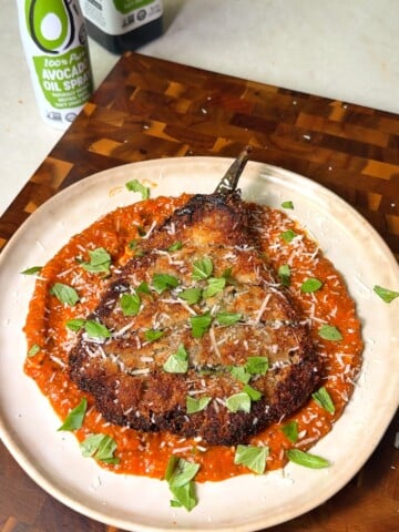 Golden panko-crusted fried eggplant cut open to show the tender interior over roasted tomato marinara