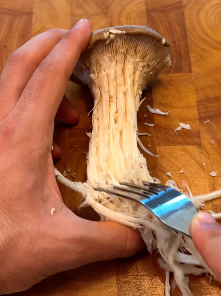 Shredding king oyster mushrooms with a fork