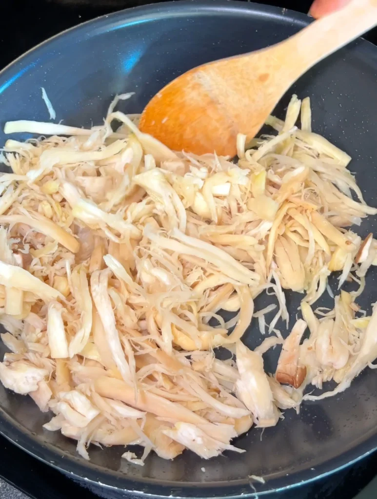 Cooking shredded king oyster mushrooms in a pan