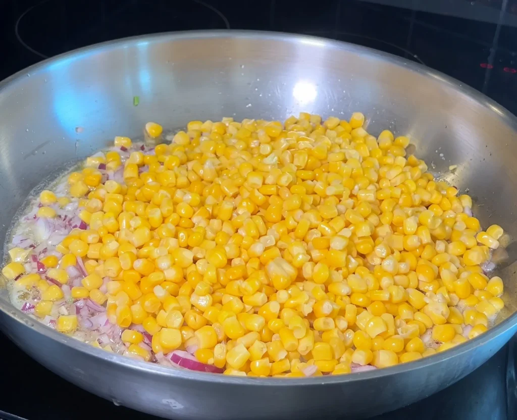 Sautéing corn and red onions in a skillet