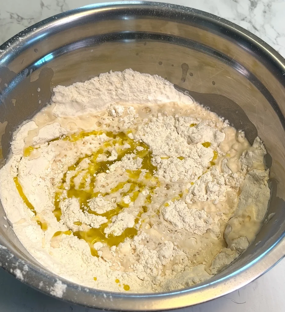 Mixing flour, water, and olive oil in a bowl to prepare empanada dough