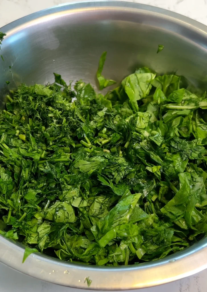 Chopped spinach and herbs in a bowl for empanada filling