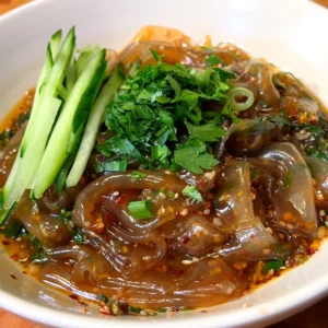 picy glass noodles in chili oil topped with fresh cucumber and parsley