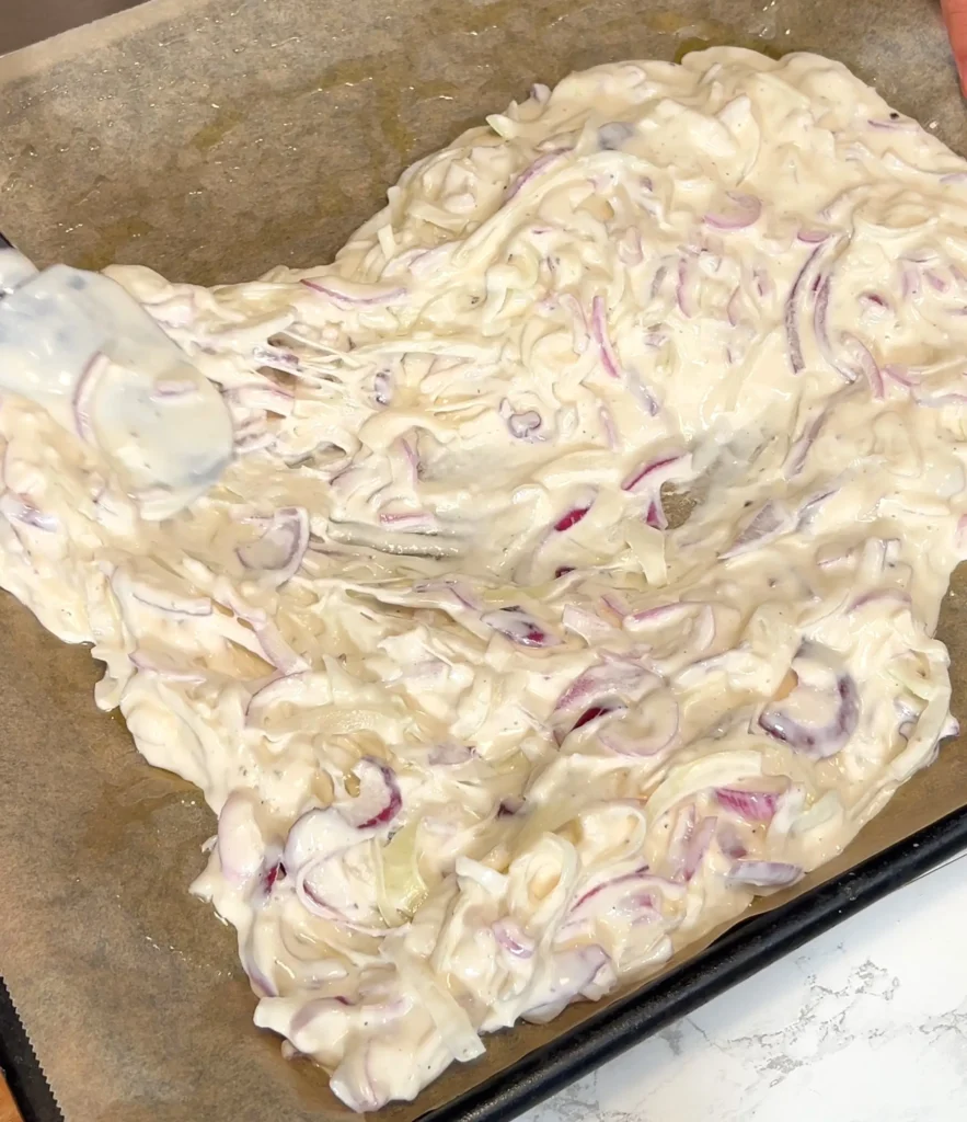 Schiacciata dough with onions spread on parchment paper, ready for baking