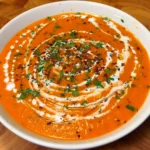Creamy roasted sweet potato and pepper soup garnished with herbs and cream.