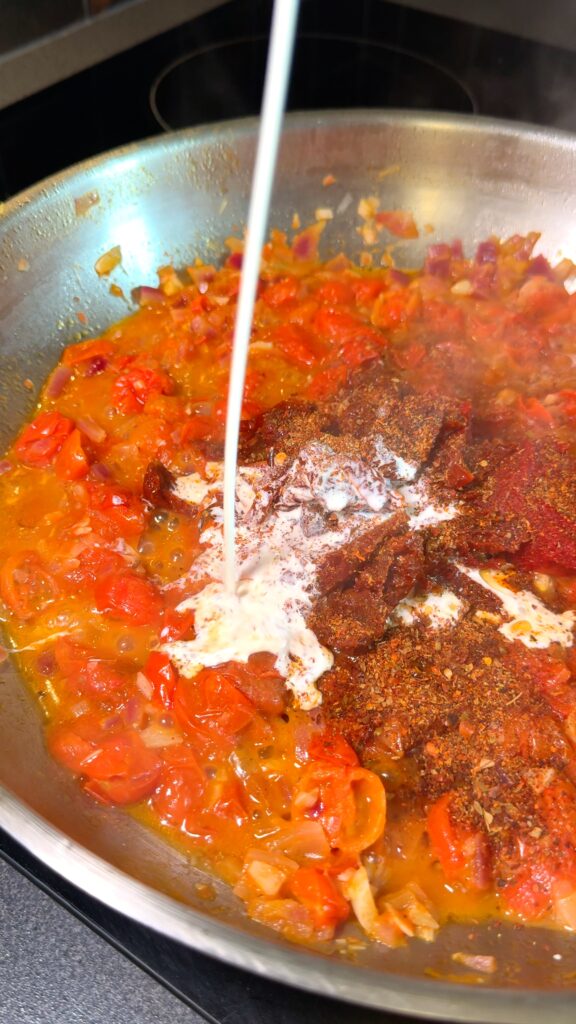 Stirring in tomato paste, sun-dried tomatoes, seasoning, salt, and pepper.