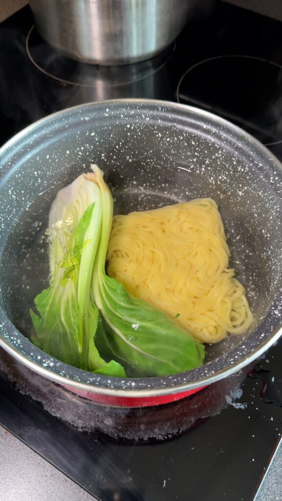 bok choy and noodles being cooked in a pot