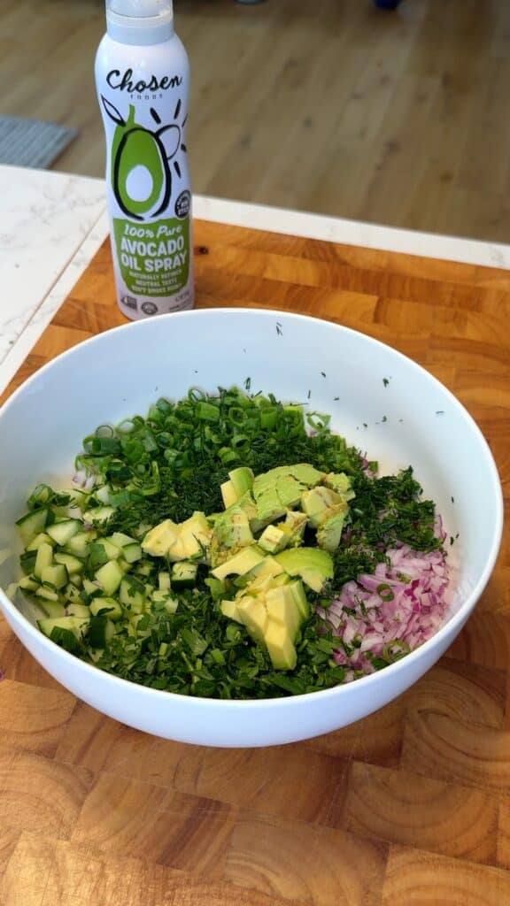 Add cucumber, red onion, spring onions, parsley, dill, and avocado to the dressing and toss gently.