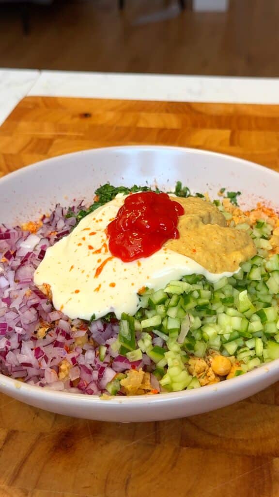 Stir in the creamy base (mayo or tahini), mustard, sriracha, herbs, veggies, and seasonings.