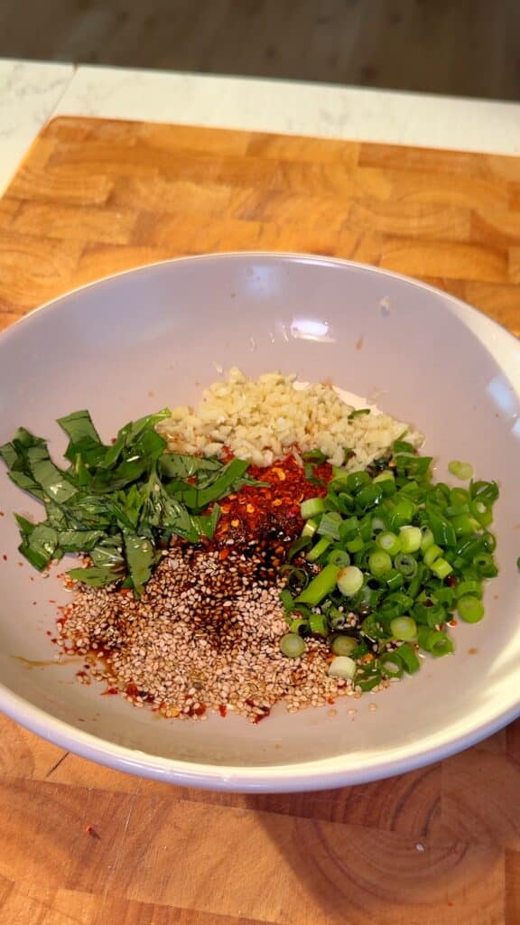 Prepare the Sauce Base
 Mix garlic, green onions, herbs, sesame seeds, chili flakes, soy sauce, vinegar, sesame oil, and sugar in a heatproof bowl.