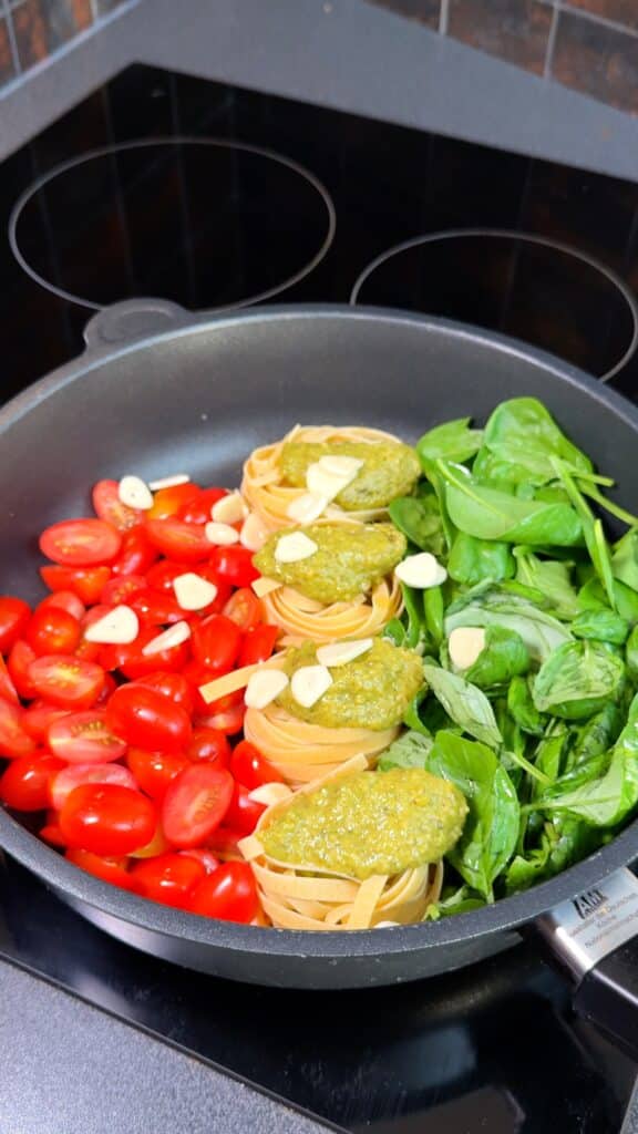 Layer Ingredients:
 In a wide pan, place pasta nests in the center. Arrange cherry tomatoes on one side and spinach with basil on the other. Scatter sliced garlic on top.