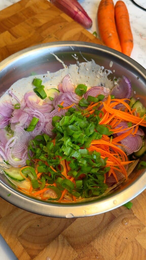 Prep the vegetables: Thinly slice the cucumber and shallot, julienne or shred the carrots, and chop the spring onions.