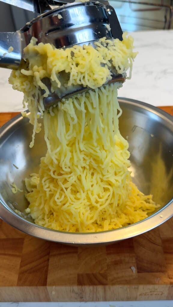 Silky mashed potatoes prepared with a ricer in a mixing bowl