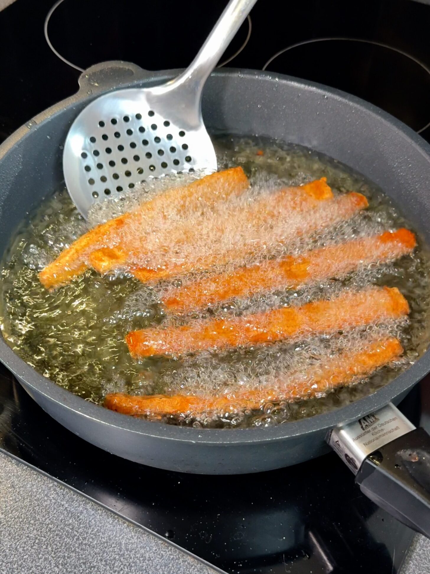 Golden brown fries frying in oil in a deep pan until crispy