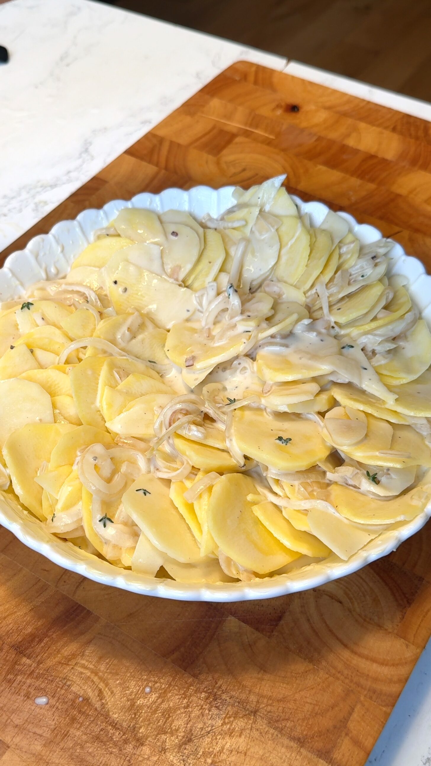 Thinly sliced potatoes coated in cream sauce in a scalloped potato baking dish