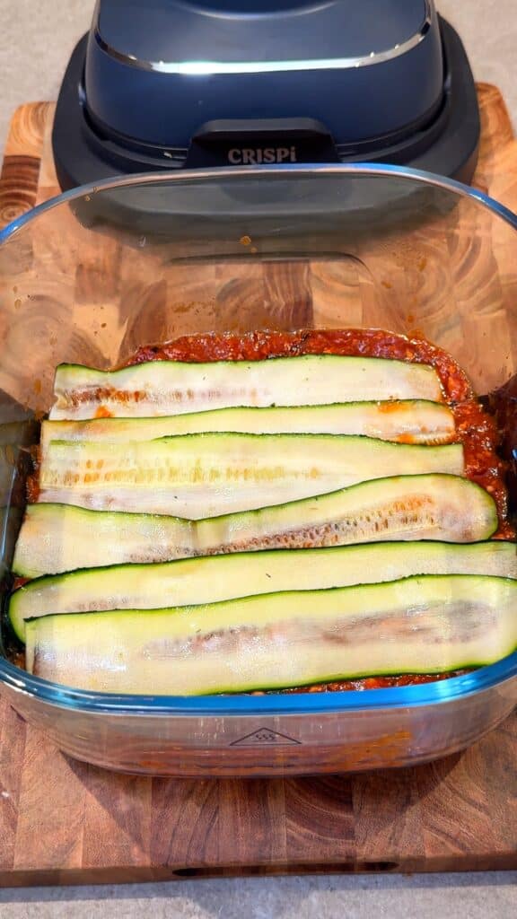 Start with sauce and zucchini Spread tomato sauce in the baking dish and add a layer of zucchini slices on top.