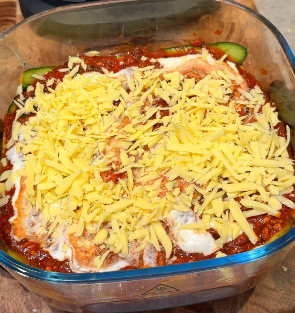 Repeat the layers and top with cheese Continue layering zucchini, tomato sauce, and white sauce until used up, then finish with shredded cheese.