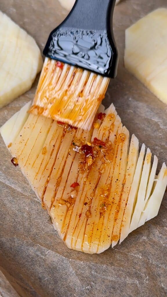 Brushing the potato plank
Brush the garlic-herb oil generously into all the cuts and along both sides. Those grooves catch seasoning and help it turn golden in the oven.