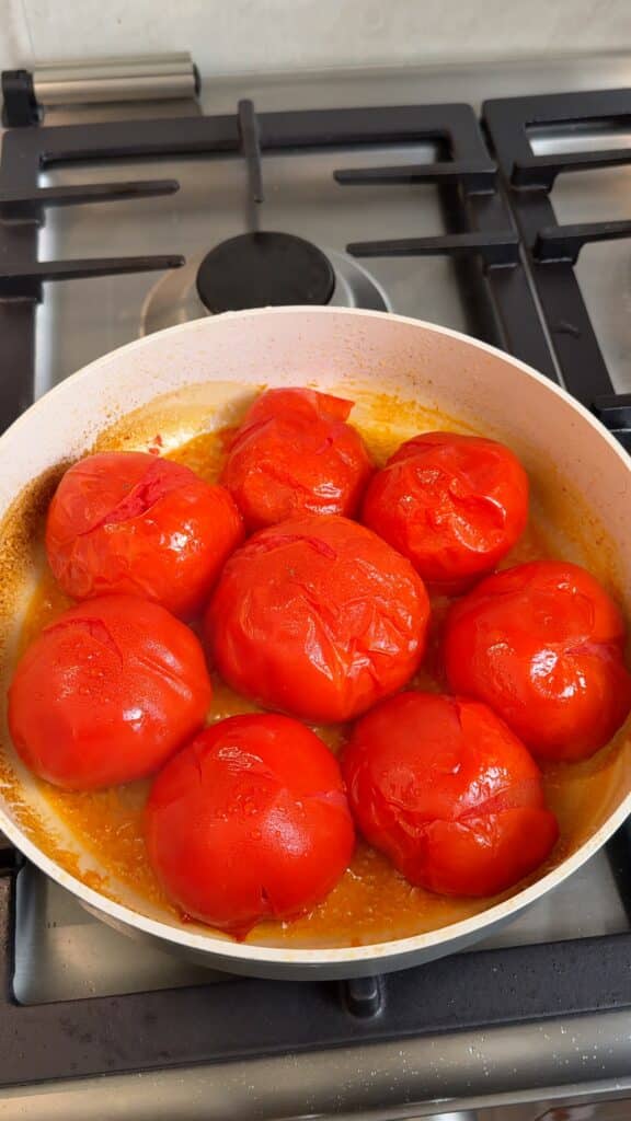 Cook the whole tomatoes
Add whole tomatoes to a wide pan with olive oil, cut side down. Cover and cook until the skins soften.