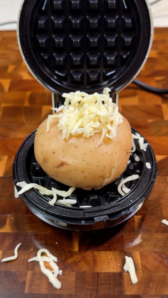 Layer potato and cheese
Add grated vegan cheese to the waffle iron, place the boiled potato on top, then cover with more cheese.