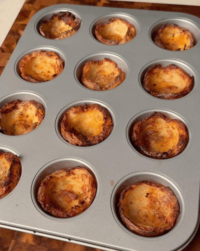 Shape and bake the potato cups
Press each boiled potato into a greased muffin tin with a shot glass. Drizzle with oil, season, and bake until deeply golden and crispy.
