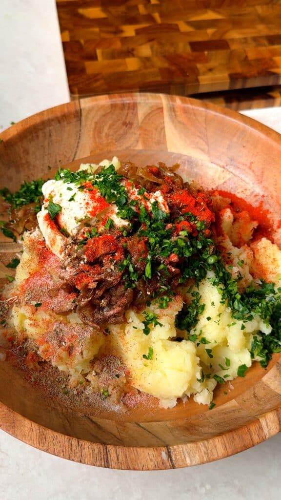 Make the fillingMash the potato flesh with caramelised onions, vegan cream cheese, parsley, smoked paprika, and spices.