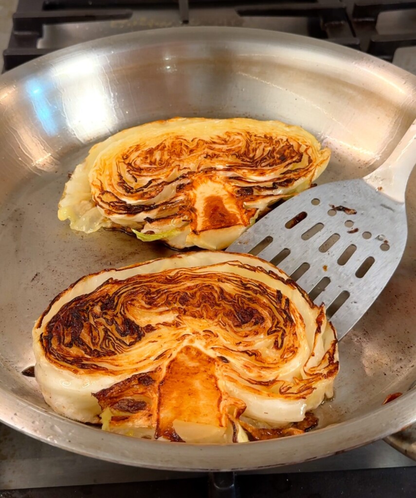 Sear the cabbage steaks Season thick cabbage slabs with salt. Sear in olive oil until deeply golden and charred. Remove and set aside.