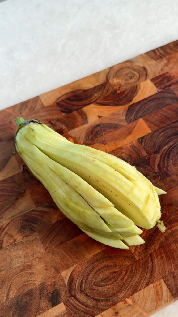 Cut into strips Peel the eggplant and slice lengthwise into thick fry-shaped strips, keeping the stem end intact.