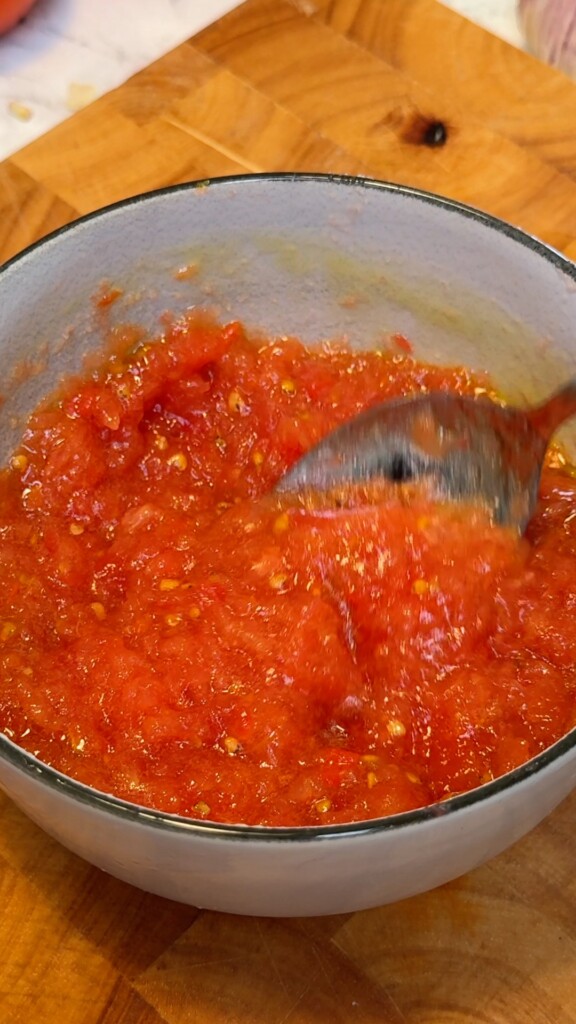 Bowl of seasoned grated tomato pulp with olive oil and salt ready for Spanish tomato bread