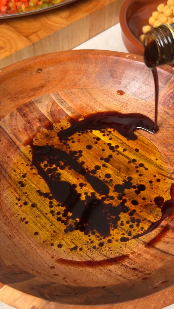 Pomegranate molasses being whisked into olive oil for balela dressing