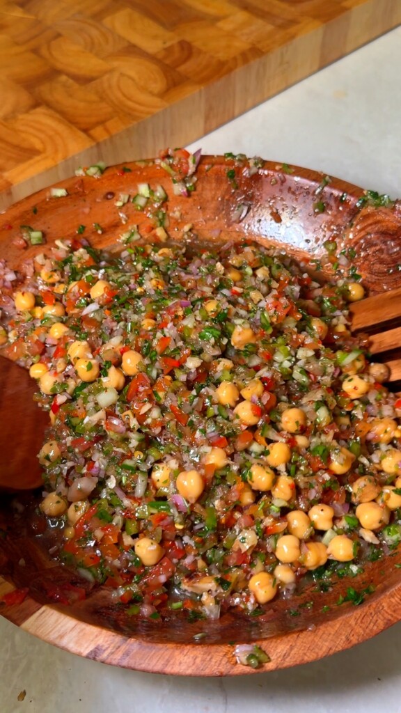 Tossed Lebanese balela salad with sumac and herbs in a wooden bowl
