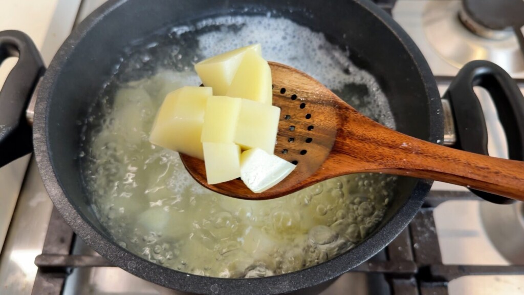 Cubed potatoes boiling in a pot of salted water for crispy breakfast potatoes