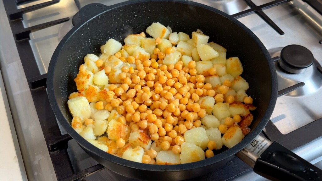 Crispy golden potatoes with drained chickpeas added to the skillet, ready to cook together
