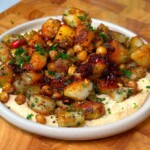 Crispy breakfast potatoes with chickpeas served over hummus, drizzled with chili crisp and parsley