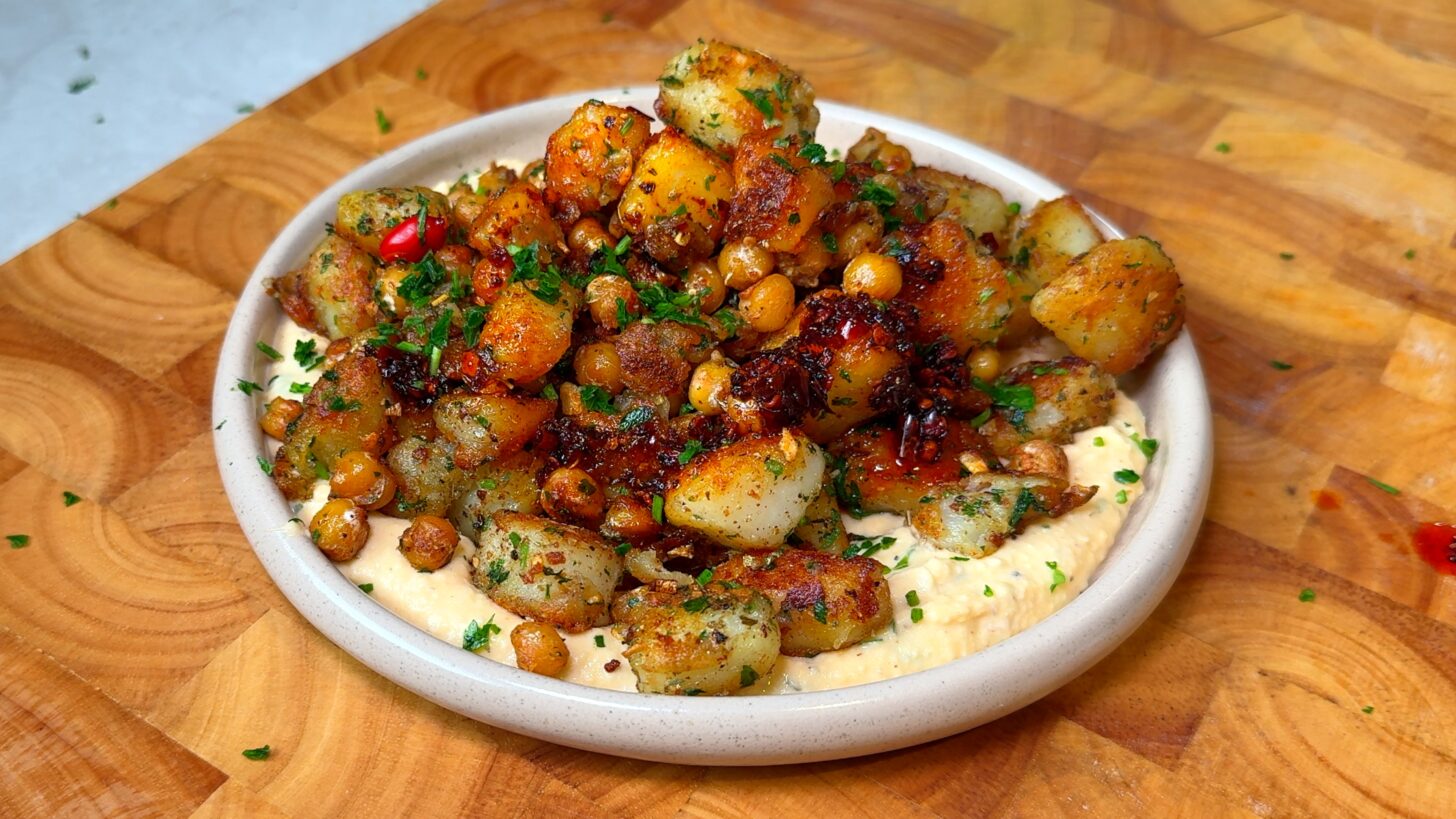 Crispy breakfast potatoes with chickpeas served over hummus, drizzled with chili crisp and parsley