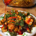 Mediterranean roasted vegetables with crispy chickpeas over hummus, drizzled with chili crisp