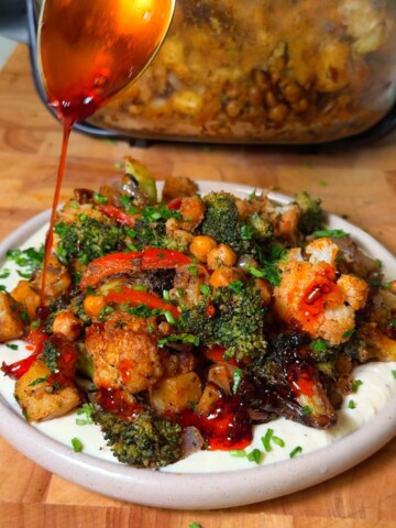Mediterranean roasted vegetables with crispy chickpeas over hummus, drizzled with chili crisp