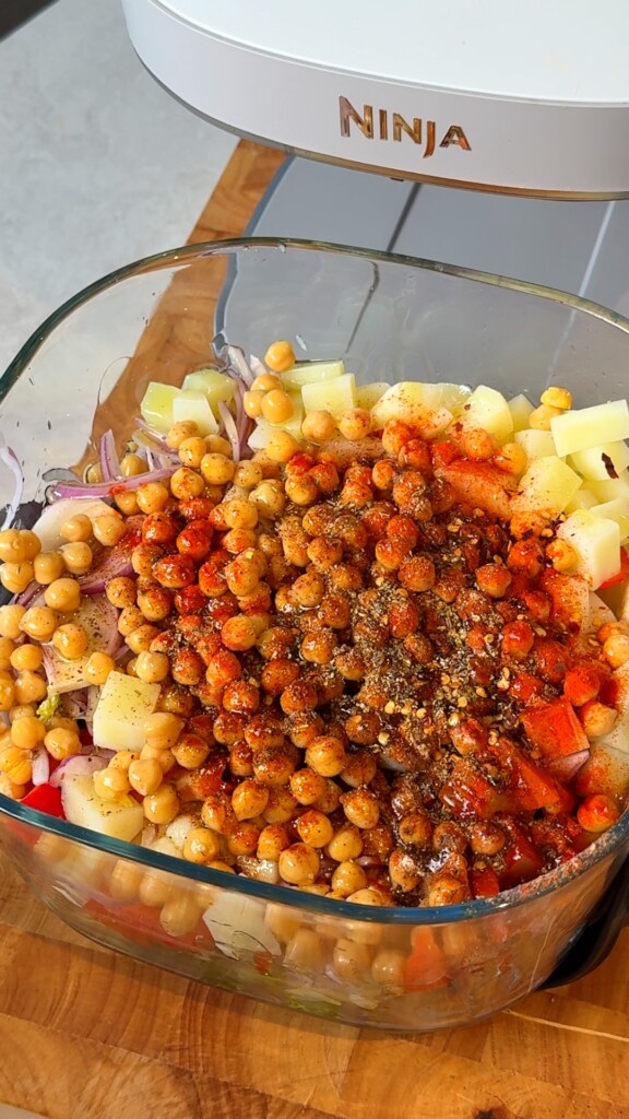 Par-boiled vegetables, bell pepper, red onion, and chickpeas tossed with olive oil and Mediterranean spices in a large bowl