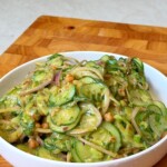 Viral cucumber salad with chickpeas, avocado, and red onion in a creamy dressing, served in a white bowl.