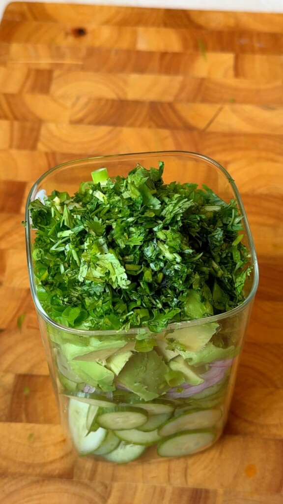 Diced avocado and chopped fresh herbs layered over cucumber and onion