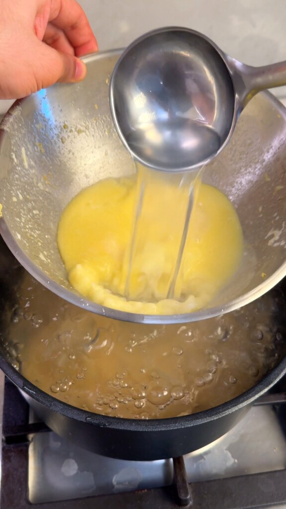 Starchy pasta water being ladled straight from the pot into the lemon butter sauce