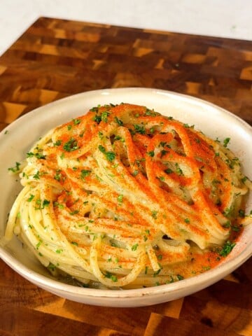 Close-up of blended garlic confit spaghetti twirled in a bowl with a red chili dusting