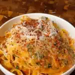 Creamy zucchini pasta in a bowl topped with vegan parmesan and chili flakes