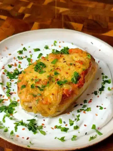 Vegan loaded baked potato stuffed with lentils and tofu, topped with melted vegan cheese and served over garlicky yogurt