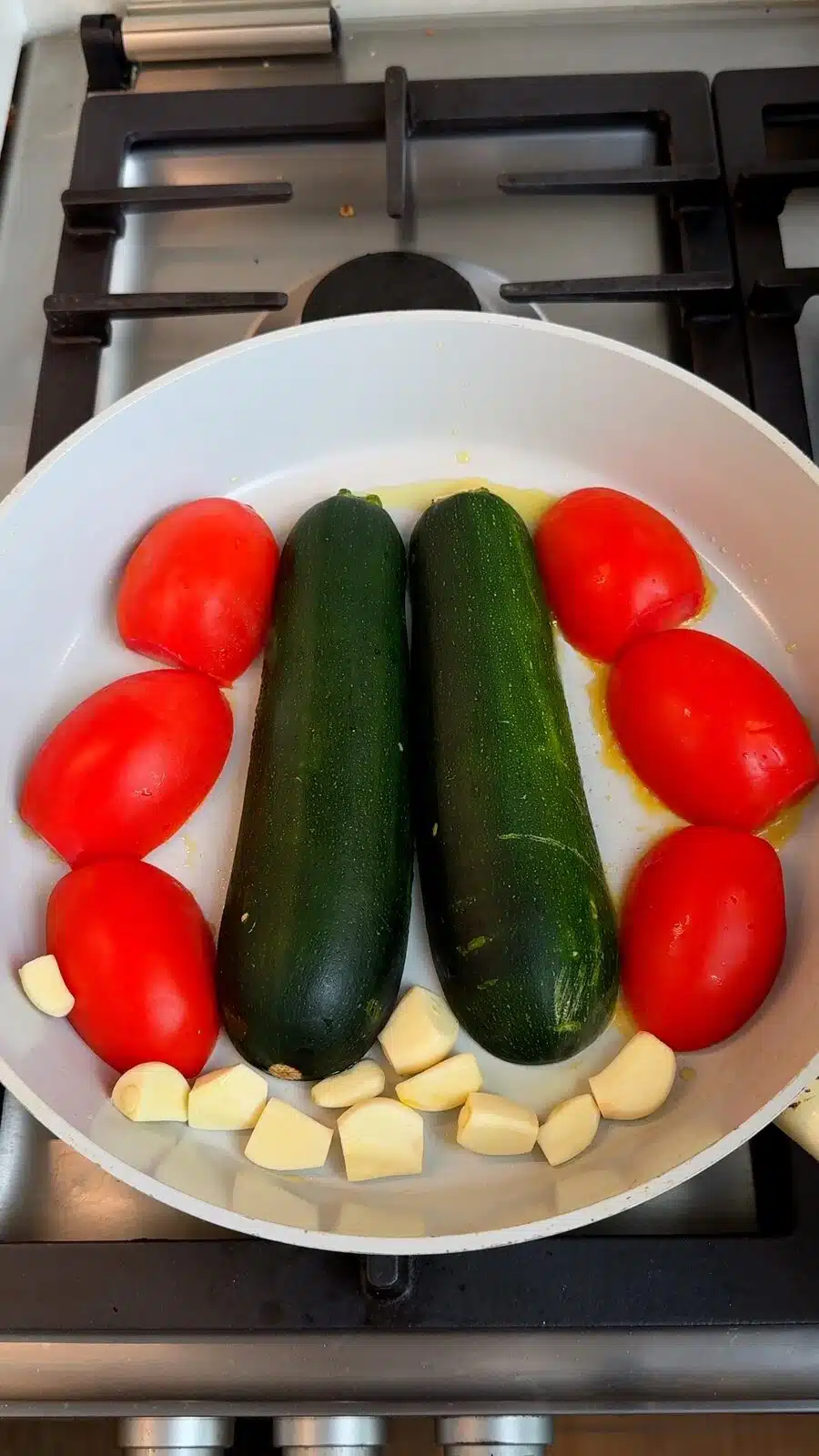 Zucchini, tomatoes, and garlic softening in a deep pan
