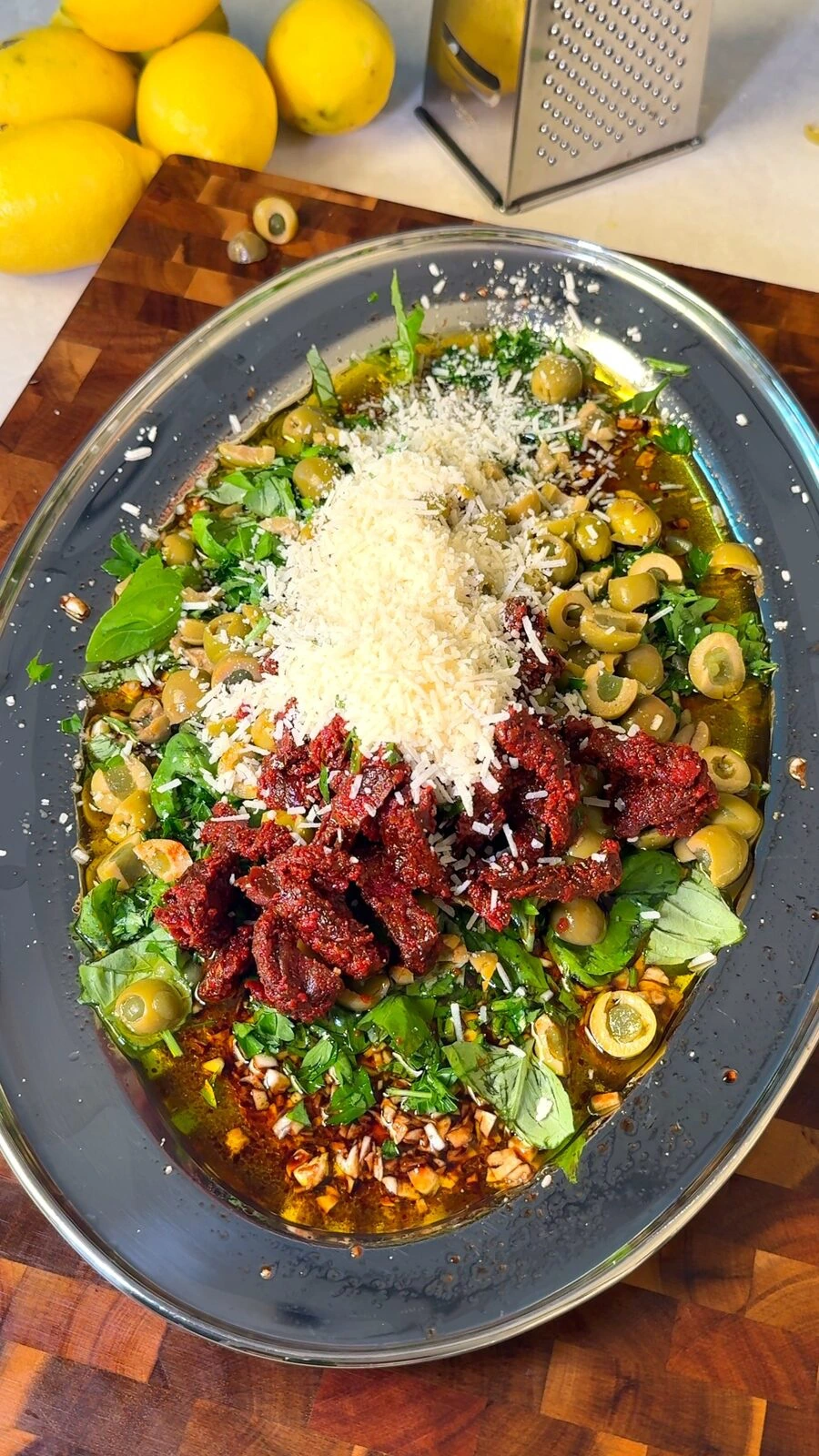 Green olives, sun-dried tomatoes, herbs, and vegan parmesan added to the bowl