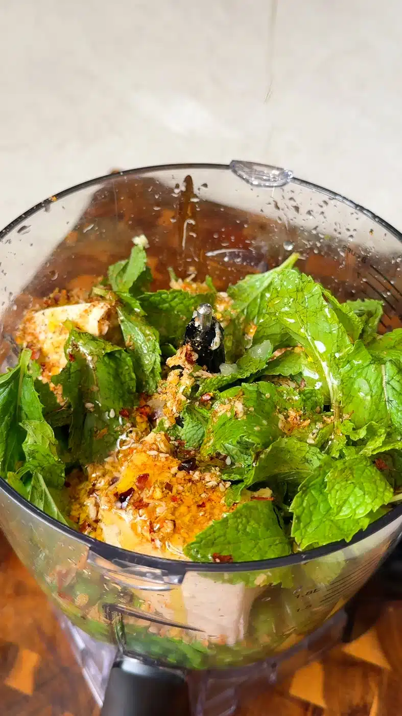 Fresh mint leaves, spices, nutritional yeast, and olive oil added on top of peas and tofu for pea pesto toast