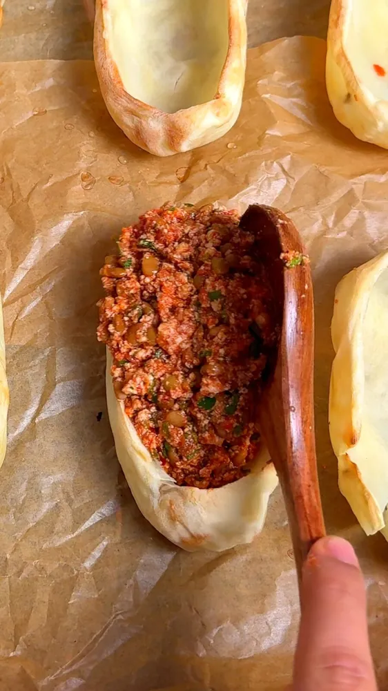 Lentil and tofu filling being spooned into a baked potato boat