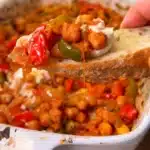 Mediterranean chickpea and pepper bake scooped onto crusty bread