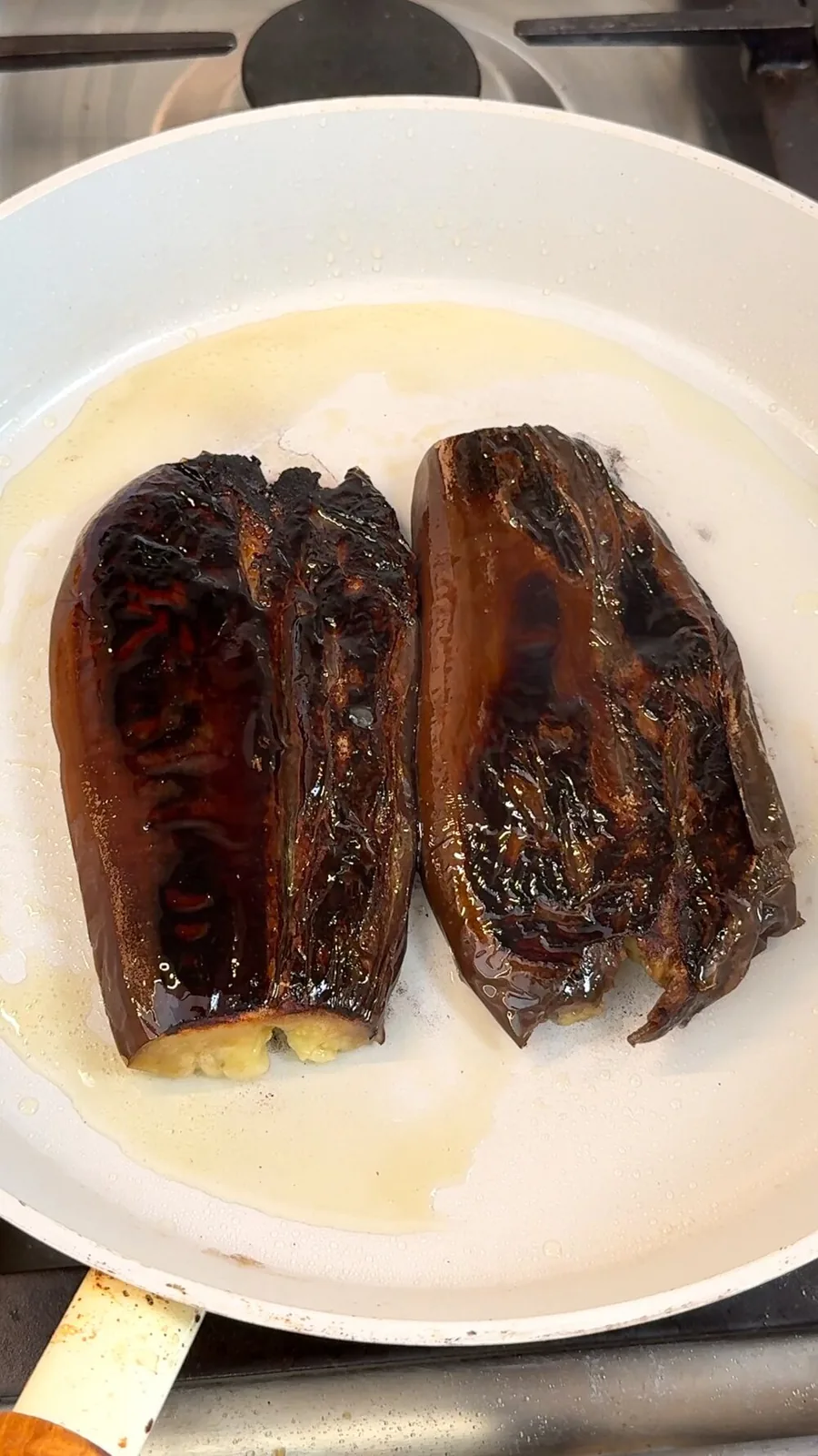 Scored eggplant searing in a pan